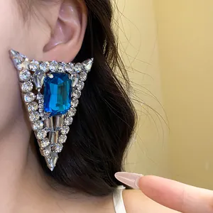 Detailed view of a large triangular silver stud earring with blue crystal and pave rhinestones