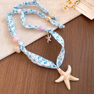 Detail of ocean-style scarf necklace with starfish and shell pendants on wood background.