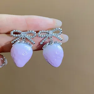 Macro view of sweet purple resin strawberry earrings featuring silver zircon bow detail