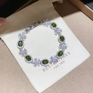 Elegant silver flower bracelet featuring green zircon stones displayed on gift pouch