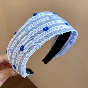 Dettaglio di cerchietto largo in tessuto a righe blu e bianche con pois decorativi