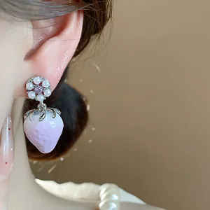 Macro detail of sweet purple resin strawberry earrings with elegant pearl floral accents
