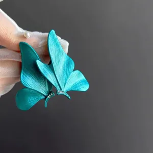 Gros plan sur d'élégantes boucles d'oreilles papillon bleu sarcelle avec petits cristaux.