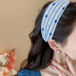 Dettaglio di una fascia larga a righe blu con ricamo floreale su una modella asiatica