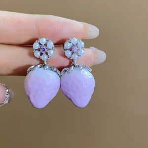 Detail of purple strawberry resin earrings with pearl and zircon flower accents