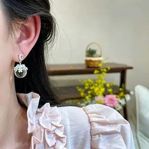 Close-up of a model wearing a translucent bulb earring with colorful drip-oil flowers.