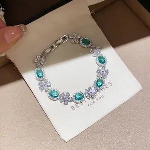 Detailed view of elegant silver flower bracelet with emerald green oval gemstones
