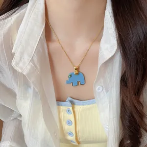 Detail view of a cute blue resin elephant pendant on a gold chain necklace worn by a model