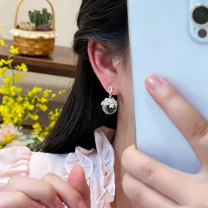 Close-up view of elegant flower-filled transparent glass ball drop stud earrings detail