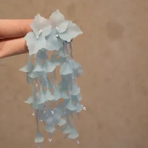 Vue détaillée d'élégantes boucles d'oreilles à fleurs en tissu bleu clair à la main