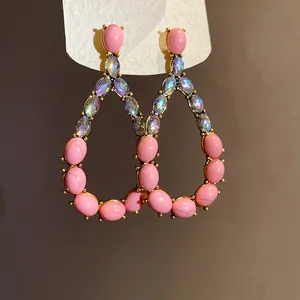 Dettaglio di orecchini vintage a goccia con pietre rosa e cristalli cangianti iridescenti