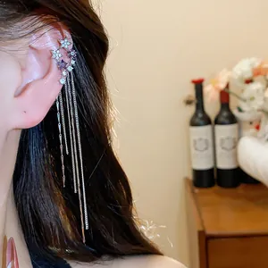 Detail view of zircon star tassel ear cuff with long dangling chains on female ear.