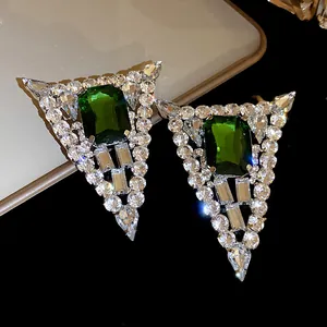 Close-up view of triangular earrings featuring a large emerald green center stone.