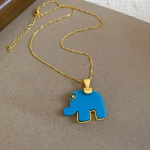 Close-up detail of a blue resin elephant pendant on a gold-plated twisted chain