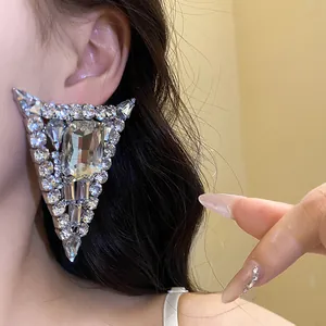 Close-up of oversized silver triangle earring with sparkling baguette and round crystals