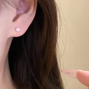 Close-up of a minimalist white pearl stud earring worn on the ear for an elegant look