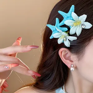 Close-up of vibrant blue starfish and white flower hair clips on model for beach style
