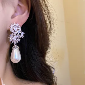 Primer plano de pendientes de circonita con elegante perla en forma de lágrima mujer