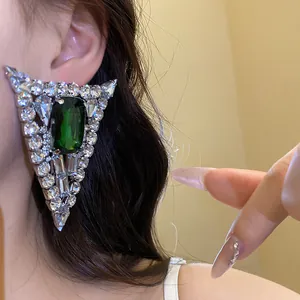 Close-up detail of a silver needle triangle earring with emerald green gemstone.