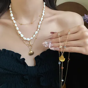 Close-up view of elegant conch and starfish pendant necklace set on model's neck and hand