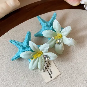 Detailed view of blue starfish and white flower hair clips with elegant crystal accents.