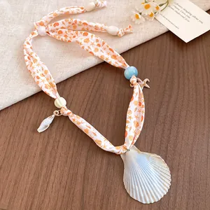 Detail of bohemian silk scarf necklace with natural scallop shell and starfish charms