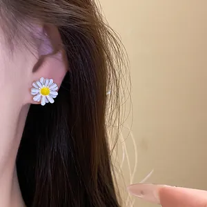 Elegant close-up view of a white enamel daisy flower stud earring worn by a model