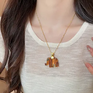 Detailed wearing effect of an elegant brown resin elephant pendant necklace on a delicate gold chain
