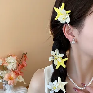 Close-up of yellow starfish and white flower hair clips on model's braid