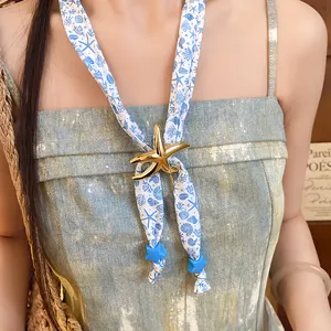 Close-up of ocean-themed starfish pendant on printed blue and white silk scarf necklace