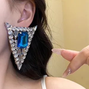 Detailed close-up of a luxury triangular earring with blue gemstone and crystals