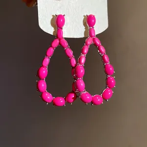 Dettaglio di orecchini a goccia rosa fucsia con pietre ovali e incastonatura in argento