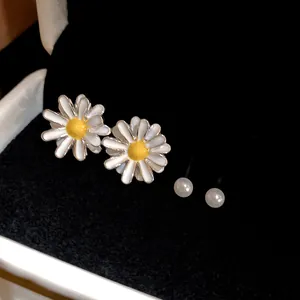 Close-up detail of elegant white daisy stud earrings with small pearls in a gift box