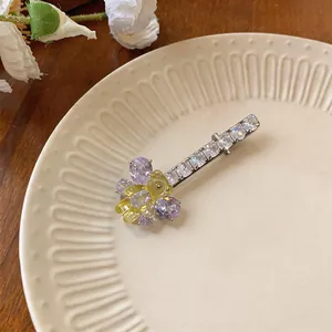 Gros plan d'une pince à cheveux élégante en zircone avec pierres violettes et petit ours