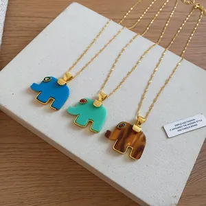 Detailed view of three resin elephant pendants in blue, teal, and amber with gold chains