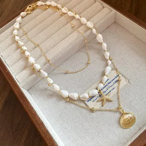 Detailed view of sea shell and starfish pendant necklace set in a wooden jewelry box.