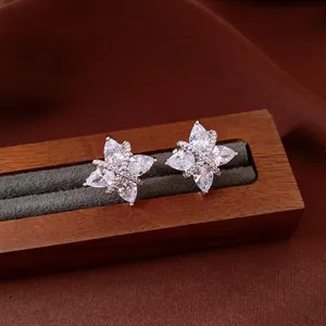 Close-up view of sparkling flower zircon stud earrings on a wooden jewelry display