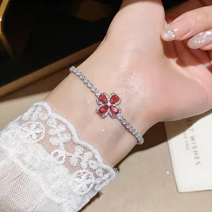 Detailed view of elegant flower bracelet featuring red zircon petals worn on a wrist.