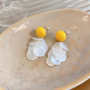 Elegante Harz-Clip-Ohrringe mit leuchtend gelbem Oberteil und weißen runden Quasten