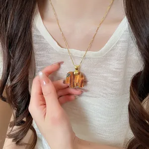 Detailed view of a brown resin elephant pendant necklace worn by a model on her neck