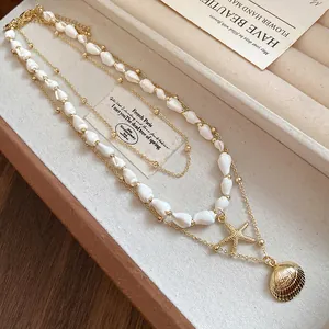 Close-up of layered shell and starfish pendant necklace in a velvet jewelry box.