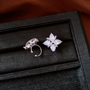Detailed view of silver-tone flower ear clips with marquise-cut zircons in a box.