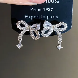 Eleganti orecchini a fiocco in ago d'argento con borchie in cristallo di zircone lucido.