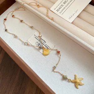 Close-up of gold shell and starfish charms on a multi-color stone beaded necklace.