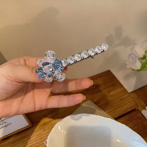 Détail d'une élégante pince à cheveux papillon en zircon avec un petit ours en résine.