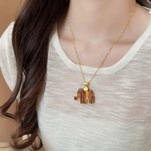 Detailed view of a dainty resin elephant pendant necklace with a gold twisted chain
