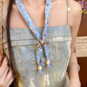 Close-up detail of ocean-themed scarf necklace with starfish and seashell patterns.