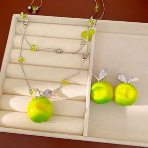 Detail view of double-layer beaded necklace and earrings with resin apple pendants