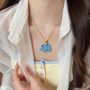 Detailed view of a light blue resin elephant pendant necklace worn by a female model