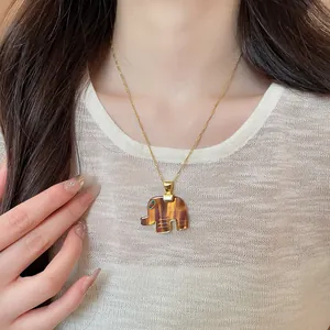Detail of resin elephant pendant necklace with tiger eye effect worn on model.